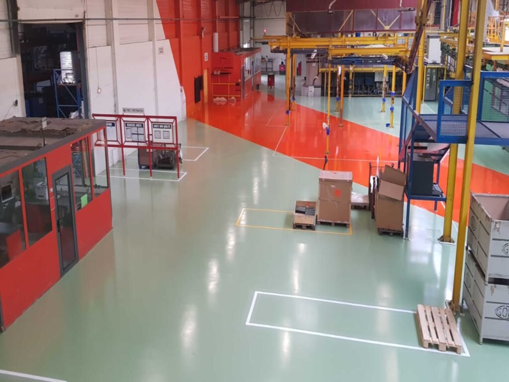 Sol en résine époxy verte et orange avec marquage blanc sur 1 200 m² dans un atelier de production.