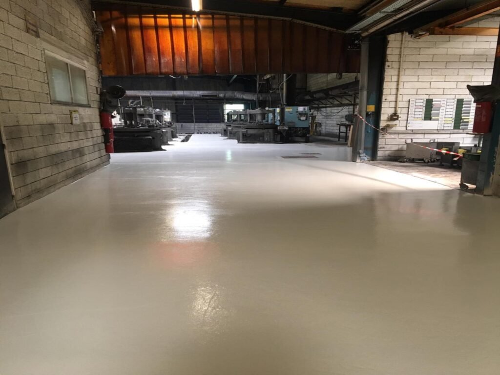 Revêtement de sol industriel en résine époxy claire sur 900 m² dans un atelier.