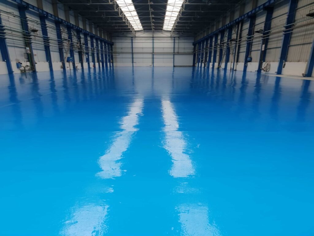 Revêtement de sol industriel en résine époxy bleue, surface brillante et résistante pour entrepôt.