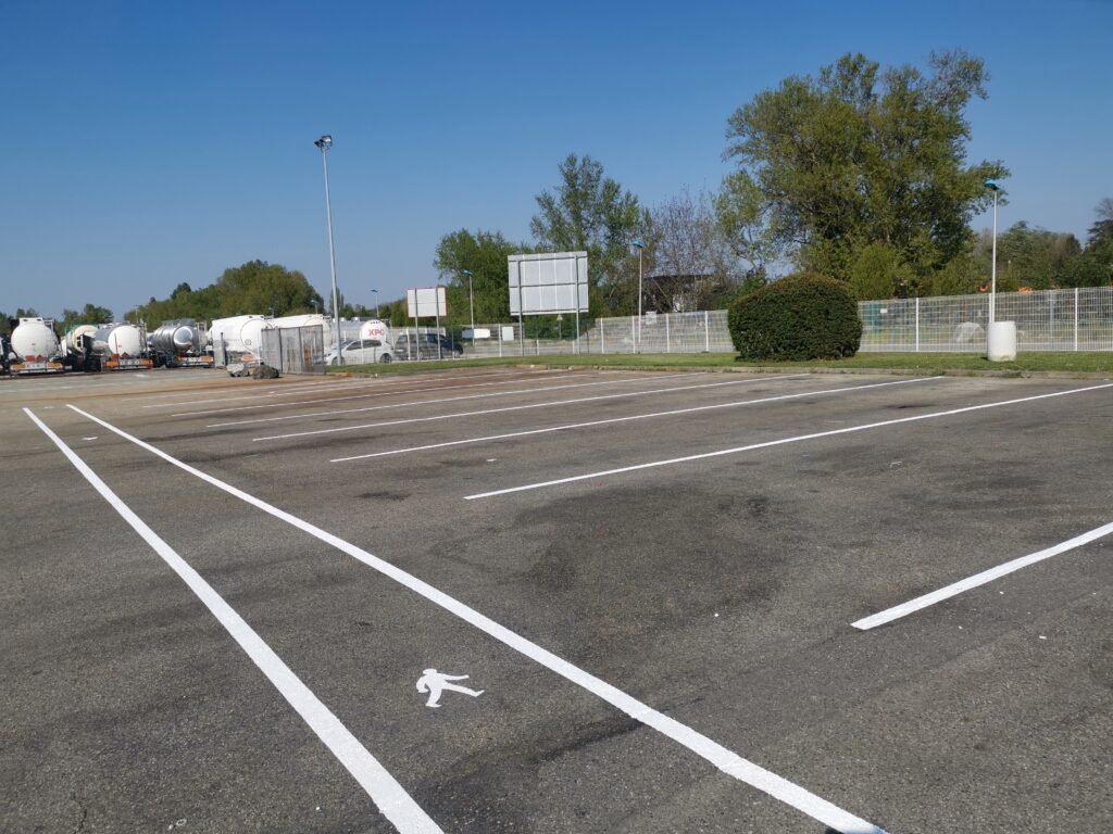Marquage au sol blanc sur parking poids lourds pour zones de stationnement et circulation.